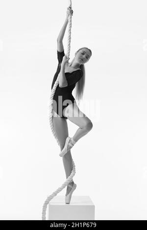 graceful ballerina in pointe shoes is posing with rope on white studio background. Black and white photo. Stock Photo