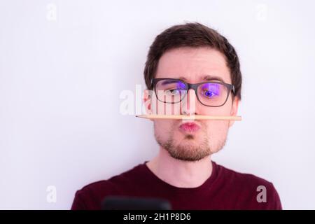 Young Caucasian man is fooling around and home, pencil trapped between nose and lips Stock Photo