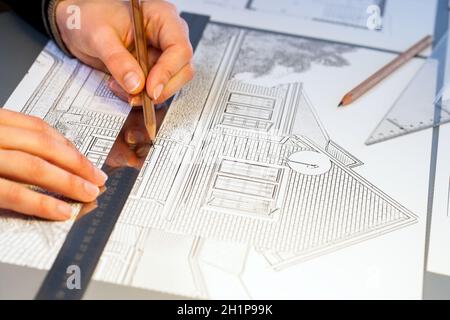 Extreme close up of human hands working on house plan project with pen and ruler. Stock Photo