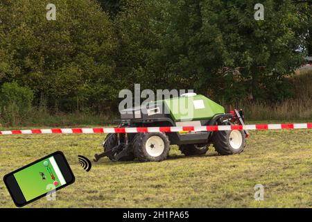 Autonomous tractor in the field. Wooden sign with inscription in German autonomous tractor. Smart farming and digital transformation in agriculture. Stock Photo