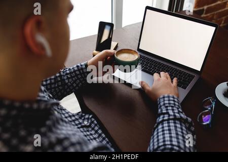 Man working at laptop with cup of coffee, headphones at home. Blurred background. High quality photo Stock Photo