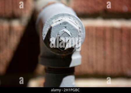 Water pipe painted grey, jutting out from a red brick house Stock Photo