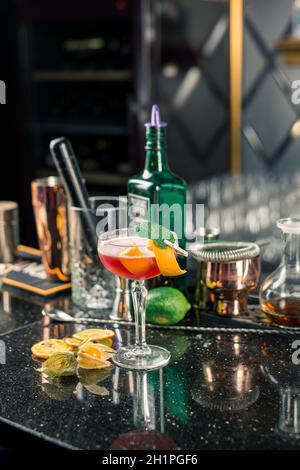 Several alcoholic cocktails at the bar in different glasses. Cocktail decoration: lime, mint, orange, syrup. Stock Photo