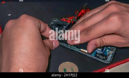 Close up of hands repairing smartphone with tools on a desk Stock Photo