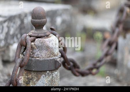 Old rusty chain connected to a concrete post Stock Photo