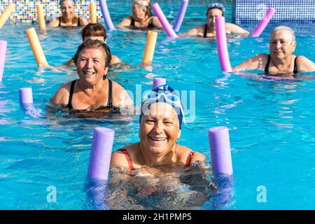 Group of active senior women doing aqua gym in outdoor swimming pool. Stock Photo