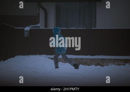Kid running on the snow during winter Stock Photo