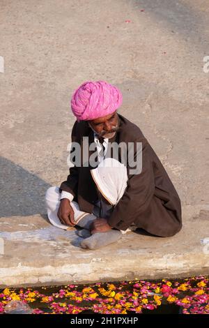 Hindu man offers prayers at the holy lakeside, Pushkar Sarovara, Hindu pilgrimage site, Rajasthan, India Stock Photo