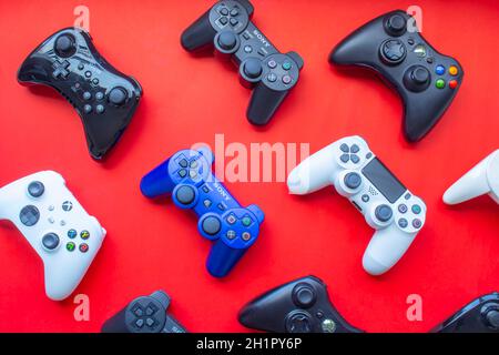 Calgary, Alberta, Canada. Feb 13, 2021. Several video game control remote from the most popular game consoles on a red background Stock Photo