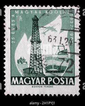 Stamp printed in Hungary dedicated to 25 anniversary of the exploitation of oil, shows Primitive and Modern Oilwells, circa 1962 Stock Photo