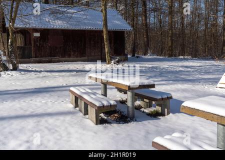 A seating group made up of two benches and a table is snowed in at a rest area in the winter forest Stock Photo