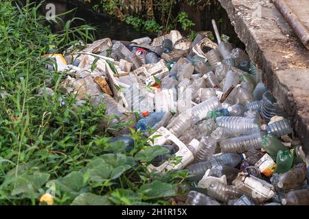 Plastic debris accumulated on a river edge with dirty water Stock Photo