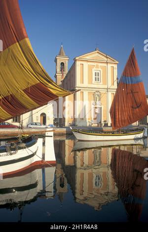 traditional fishing boats at the canale porto with the church of Saint James in the town of Cesenatico in Emilia-Romagna in Italy.   Italy, Cesenatico Stock Photo