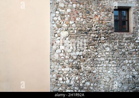 the contrast between an old stone wall flanked by a plastered wall Stock Photo