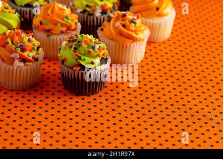 Halloween Themed Cupcakes with Sprinkles on an Orange and Black Table Stock Photo