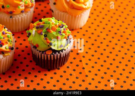 Halloween Themed Cupcakes with Sprinkles on an Orange and Black Table Stock Photo