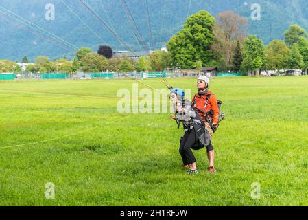 Interlaken, Switzerland - May 26, 2016: Tandem paraglider on the green lawn after landing in Interlaken, Switzerland. Stock Photo