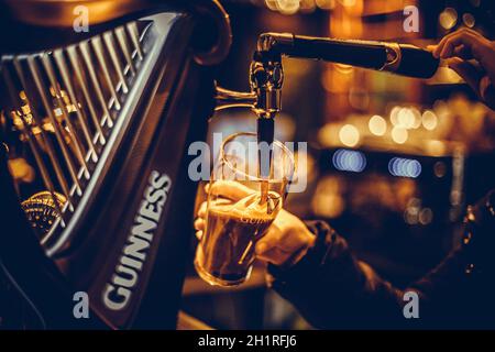Bucharest, Romania - February 25, 2021: Illustrative editorial close up image of a bartender pouring a pint of Guinness beer in a pub. Stock Photo