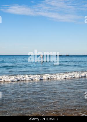 Saint-Malo, France - September 16, 2018: A man floats a board with a paddle in his hands along the beach in Saint Malo. Brittany, France Stock Photo