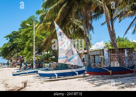 Ramena, Madagascar - December 20, 2015: Local villagers and traditional malagasy wooden sail boat piroga in Ramena, Madagascar. Ramena is a charming, Stock Photo