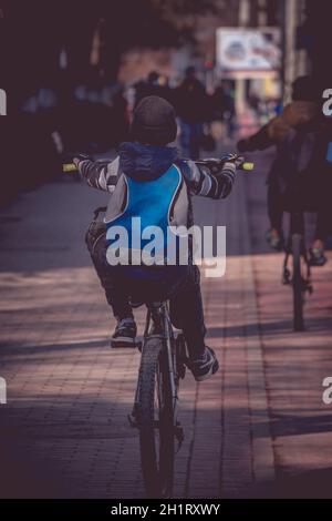 Young boy doing a wheelie with his bike on the sidewalk Stock Photo