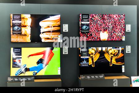 POZNAN, POL - FEB 24, 2021: Modern flat-screen TV sets by Samsung put up for sale in an electronics store Stock Photo