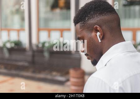 Close-up image of a guy in a profile listening to music via earbuds Stock Photo
