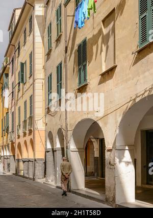 cityscape with old traditional houses over covered walkway, shot at bric-a-brac antiques street market time in  Mediterranean little town of Chiavari, Stock Photo