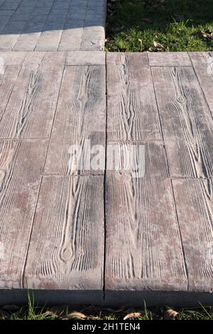 stamped concrete pavement outdoor with expansion joint at middle, wood slats pattern, flooring exterior, decorative cement paving with streaks Stock Photo