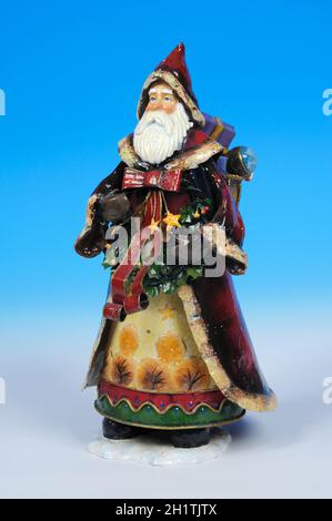 Colourful traditional tin Father Christmas statue set against a blue and white graduated background. Stock Photo