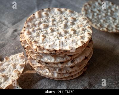 Thin round crispbreads baked with wheat, rye and barley on textile background Stock Photo