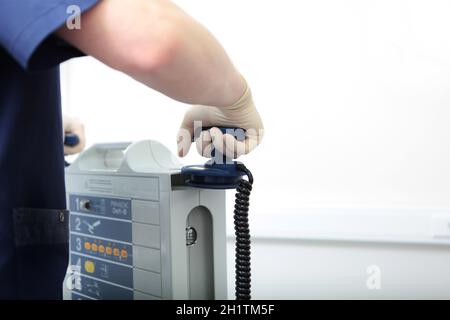 Resuscitator holds an electrode in his hand. Preparing for defibrillation. Equipping a modern clinic. Life saving concept. Beyond recognition. Stock Photo