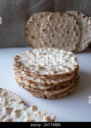 Thin round crispbreads baked with wheat, rye and barley on white and textile background Stock Photo