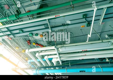 Electrical conduit system and galvanized steel pipe of electric cable installed on ceiling. PVC plastic pipe of drainage system and clean water on ind Stock Photo