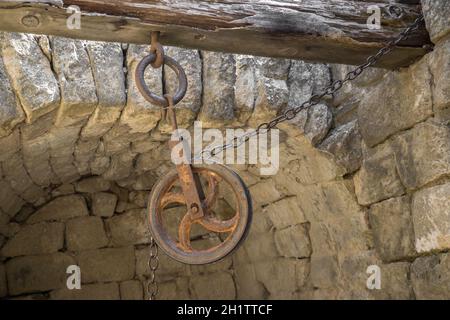 Old pulleys with chains a little rusty, fastened to a wooden beam Stock Photo