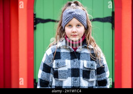 The girl comes out through the green wooden door of a colorful playhouse Stock Photo