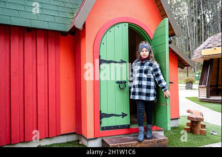 The girl comes out through the green wooden door of a colorful playhouse Stock Photo