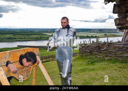Statement of medieval execution. Knightly armor and weapon. Semi - antique photo. Dramatization penalty in the middle ages. Knight swung his sword at Stock Photo