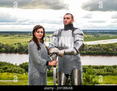 Knight with his lady in armor and chain mail. Knightly armor and weapon. Semi - antique photo. Stock Photo