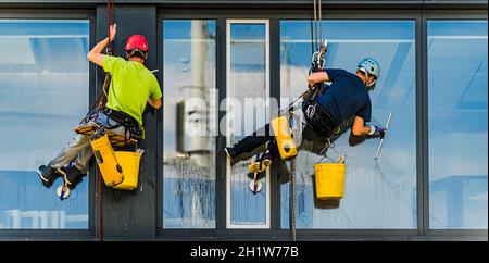 Two men cleaning windows on an office building Stock Photo