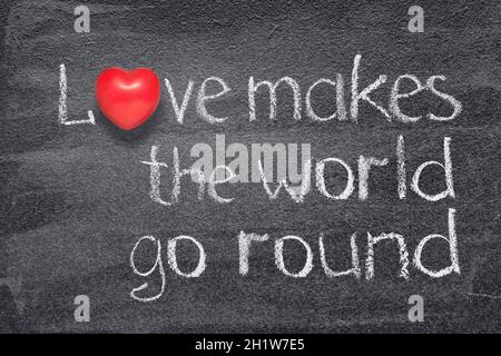 Love makes the world go round proverb written on chalkboard with red heart symbol Stock Photo