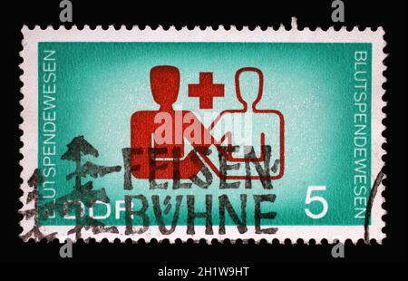 Stamp printed in Germany GDR, showing the international symbol for blood donation. Cooperation between international aid organizations and health educ Stock Photo