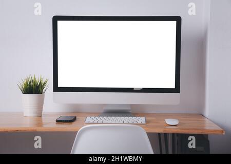 Computer monitor with white blank screen on the business desk with wireless mouse, keyboard at home office over white wall background, Photo of equipm Stock Photo