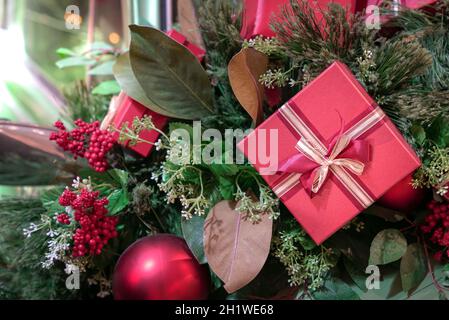Christmas presents with red ribbon hanging on tree with other decorations. Holiday concept. Stock Photo