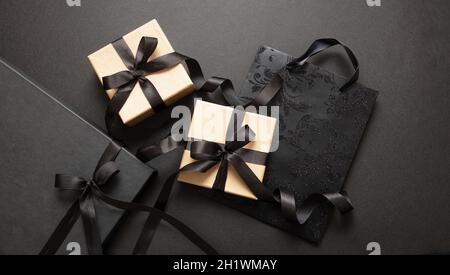 Black Friday sale concept, Gift boxes and shopping bags with tied ribbon bow on black background, top view, Winter season holiday promotion offer Stock Photo