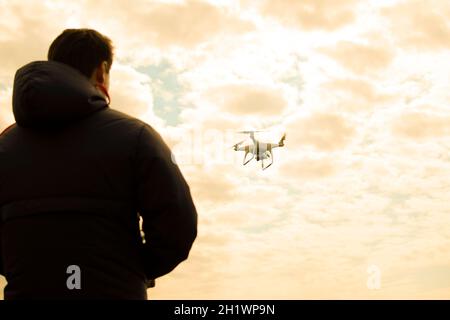 A man with a remote control in his hands. Controlling the flight of the drone against the sky. Phantom Stock Photo
