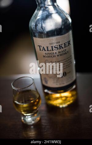 Bucharest, Romania - August 5, 2021: Illustrative editorial image of a single malt Talisker scotch whisky bottle next to a glass on counter in a pub.
