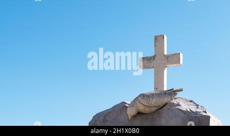 Religious stone cross against blue sky background. Stock Photo