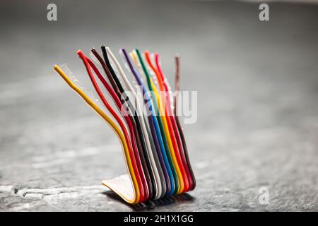 Close up of a short, bent and colorful computer ribbon cable on a rough ...