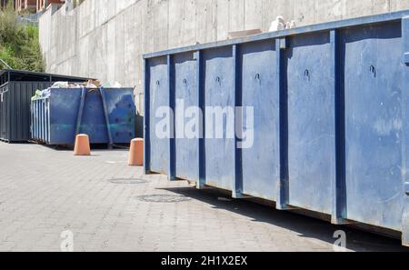 Metal durable blue industrial trash bin for outdoor trash at construction site. Large waste basket for household or industrial waste. A pile of waste Stock Photo